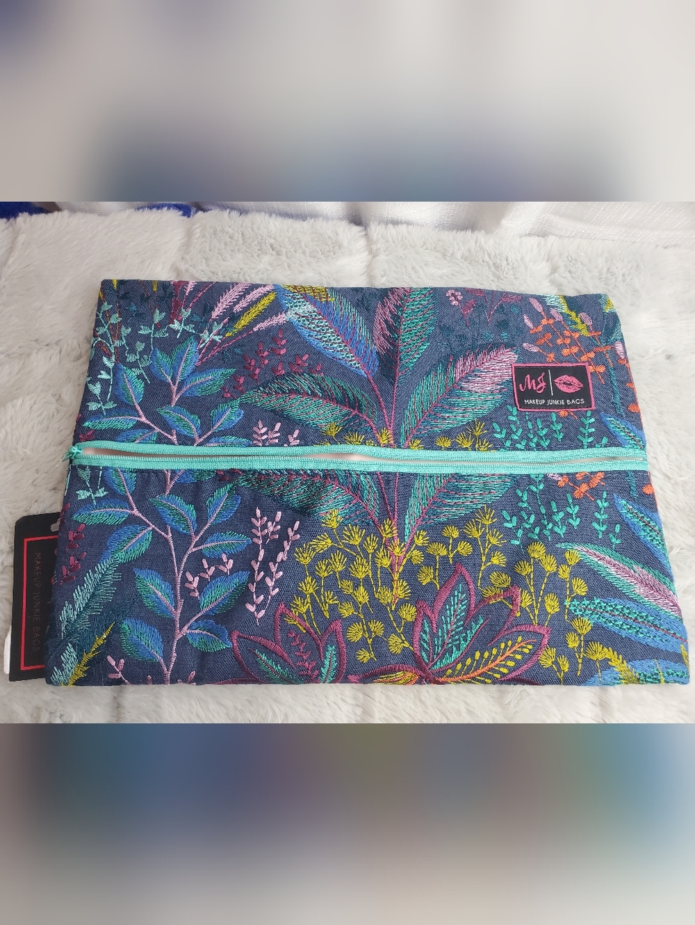 The Dreamer Large Makeup Junkie Bag is a multicolored makeup bag featuring embro